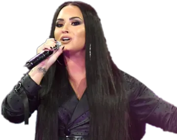 a woman with long black hair singing into a microphone