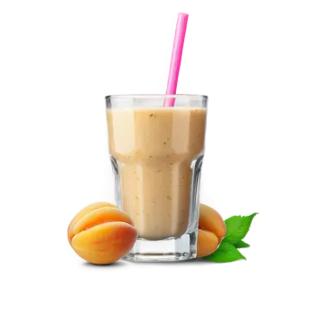 a glass of peach smoothie next to peaches