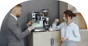 a man and woman standing in front of a coffee machine