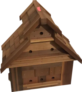 a wooden bird house with a red heart on the roof