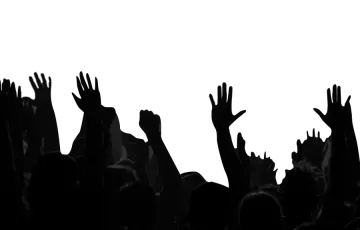 a crowd of people raising their hands in the air