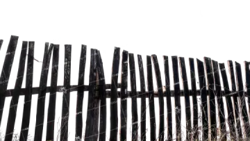 a wooden fence in front of a white sky