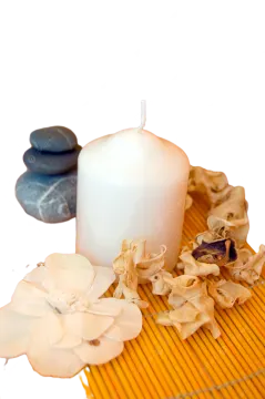 a candle and some flowers on a bamboo mat