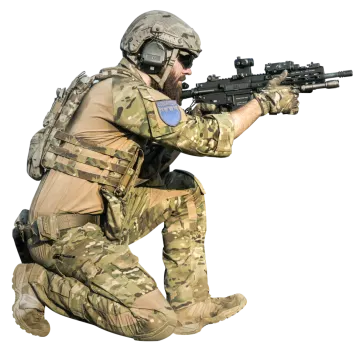 a man in camouflage gear crouching down with a rifle