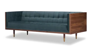 a dark blue velvet sofa with wooden legs