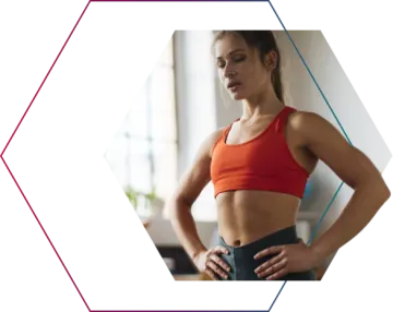 a woman in an orange sports bra top and black leggings with her hands on her hips