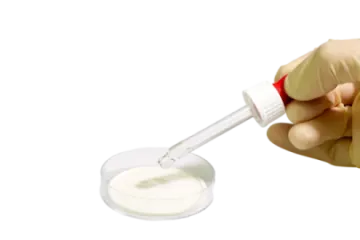 a hand holding a vial filled with white liquid