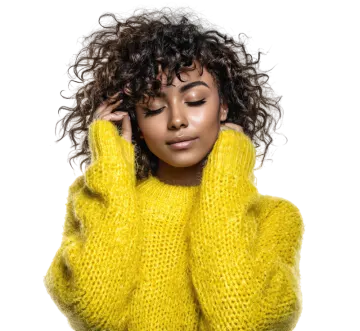 a woman with curly hair wearing a yellow sweater
