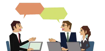 two people sitting at a table with laptops and talking