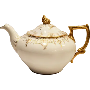 a white tea pot with gold trimming