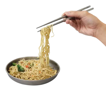 a person holding chops over a bowl of noodles