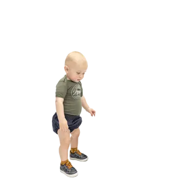 a small child in a green shirt and blue shorts