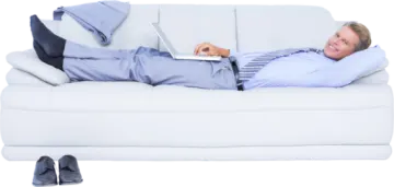 a man laying on a couch with his laptop