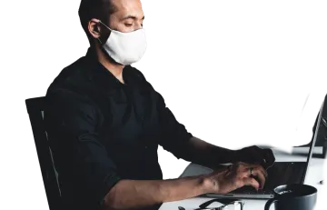 a man wearing a face mask while working on his laptop