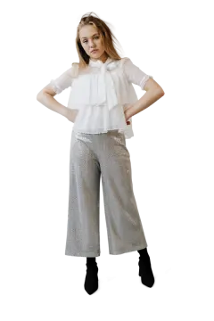 a woman wearing a white top and silver pants