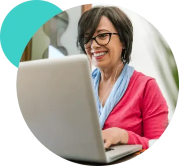 a woman sitting in front of a laptop and smiling