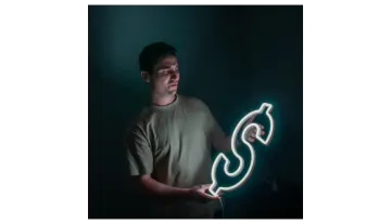 a man holding a lit up dollar sign