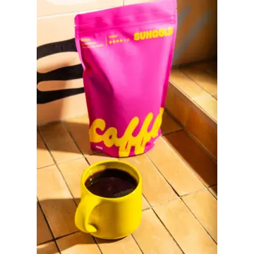 a yellow cup sitting next to a pink bag