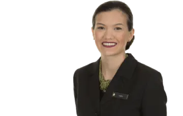 a woman in a black suit and green necklace