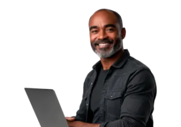 a man is smiling while using his laptop