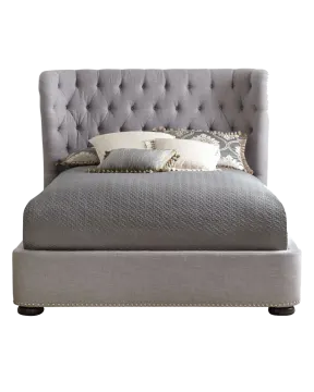 a bed with a gray headboard and pillows