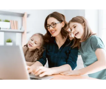 a woman and two young girls looking at a laptop