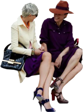 a woman in a purple dress and hat sitting next to another woman