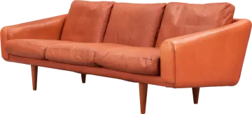 an orange leather sofa with wooden legs