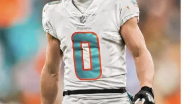 a football player wearing a white jersey and black gloves