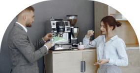a man and woman standing in front of a coffee machine
