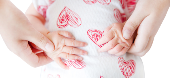 a woman holding her baby's hands with hearts drawn on it