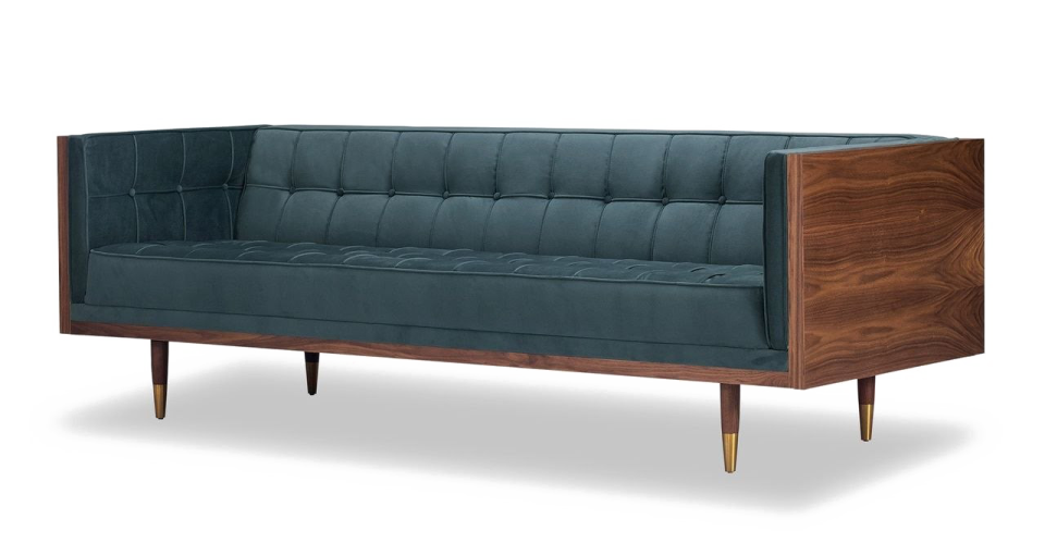 a dark blue velvet sofa with wooden legs