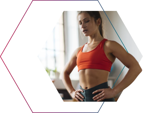 a woman in an orange sports bra top and black leggings with her hands on her hips