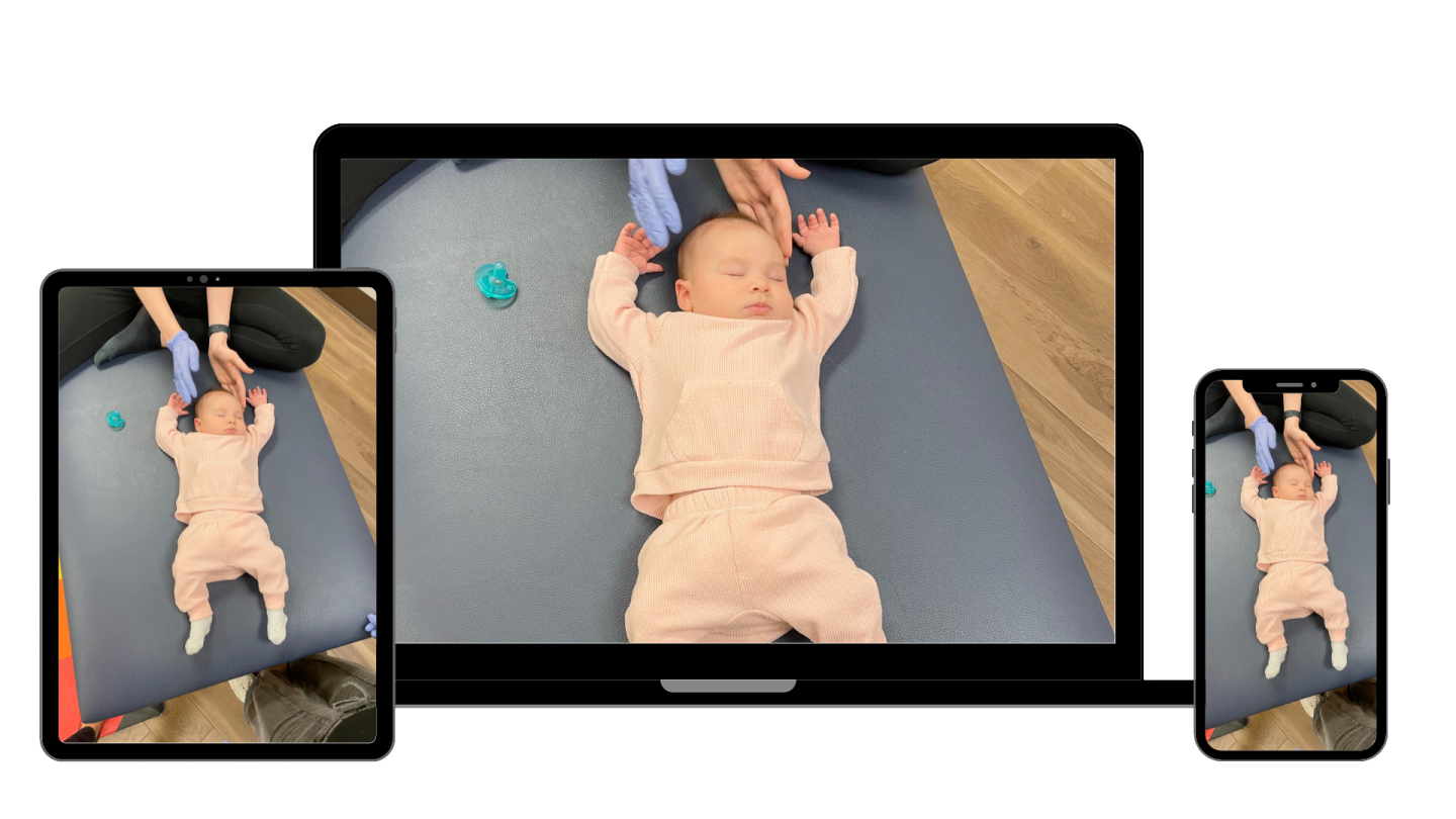 a baby laying on the floor in front of two ipads