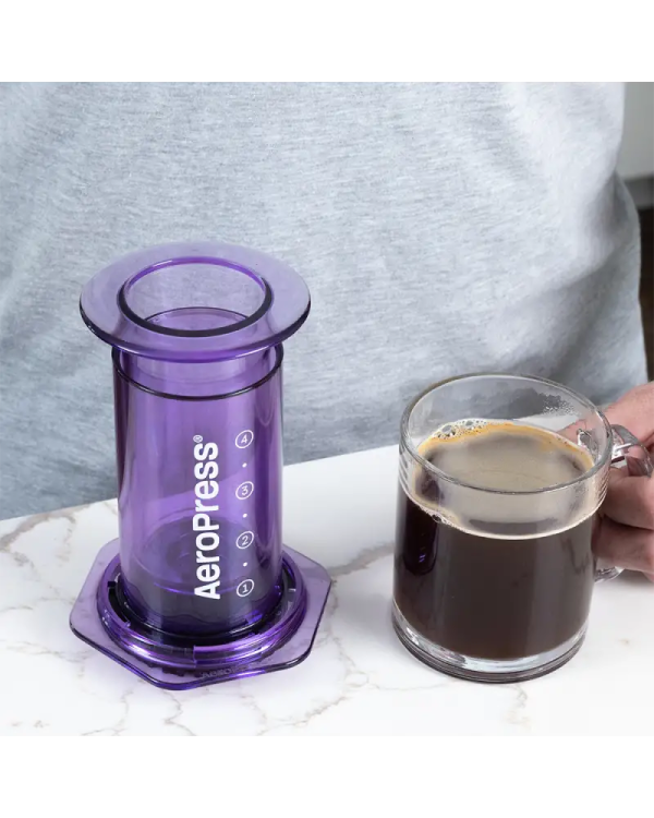 a person holding a cup of coffee in front of a glass