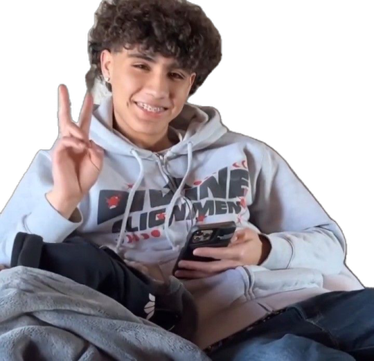 a boy sitting on top of a couch holding a cell phone