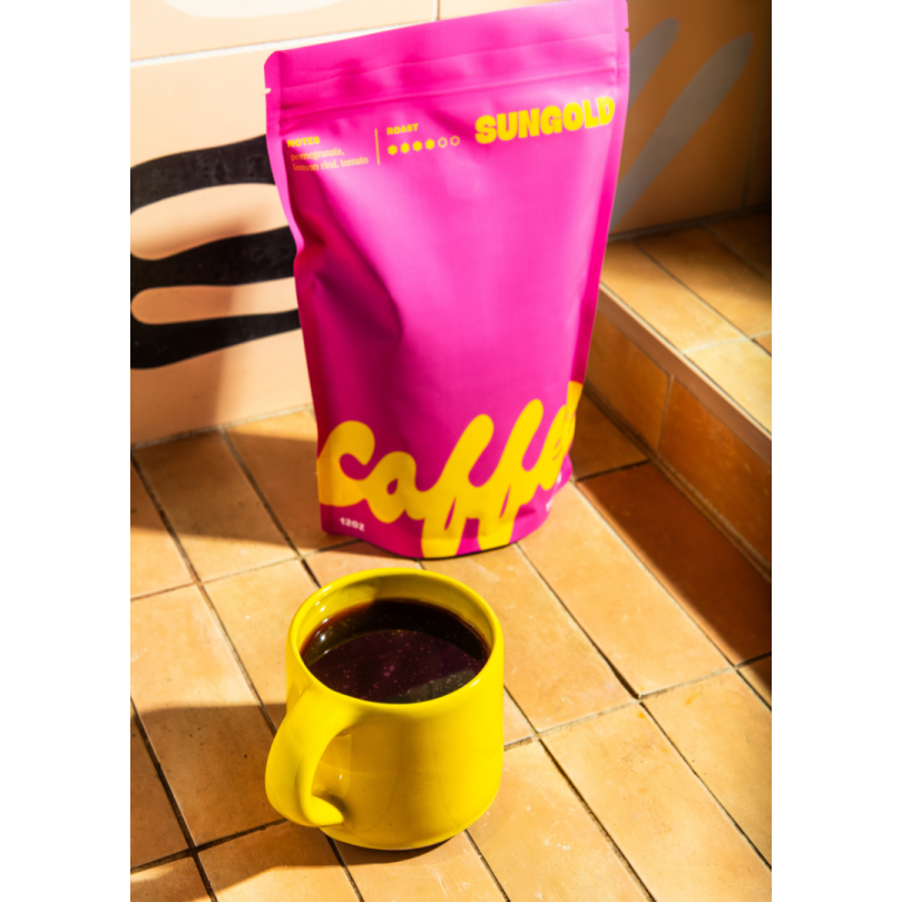 a yellow cup sitting next to a pink bag