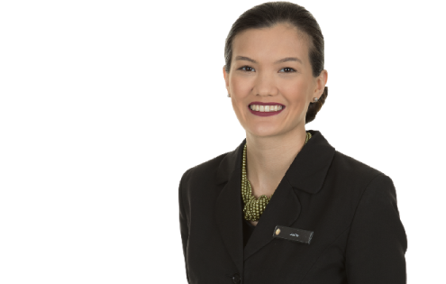 a woman in a black suit and green necklace