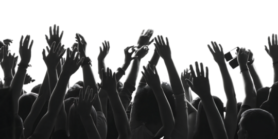 a crowd of people raising their hands in the air